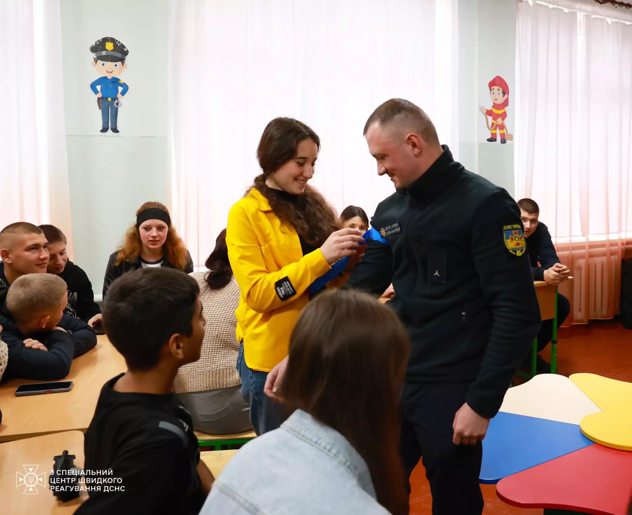 На фото старшокласниця накладає турнікет на руку рятувальнику