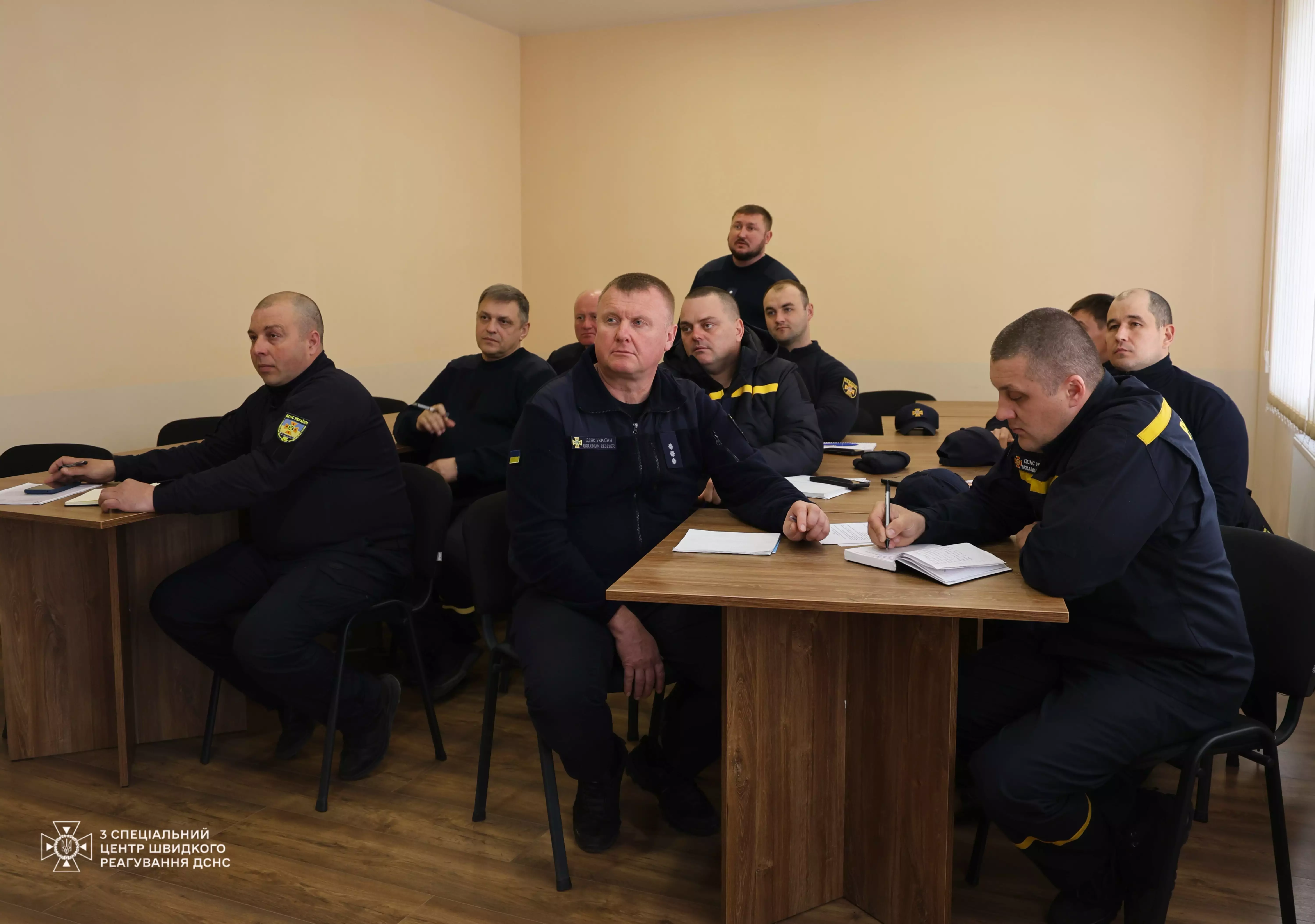На фото зображені рятувальники на навчальному занятті за столами