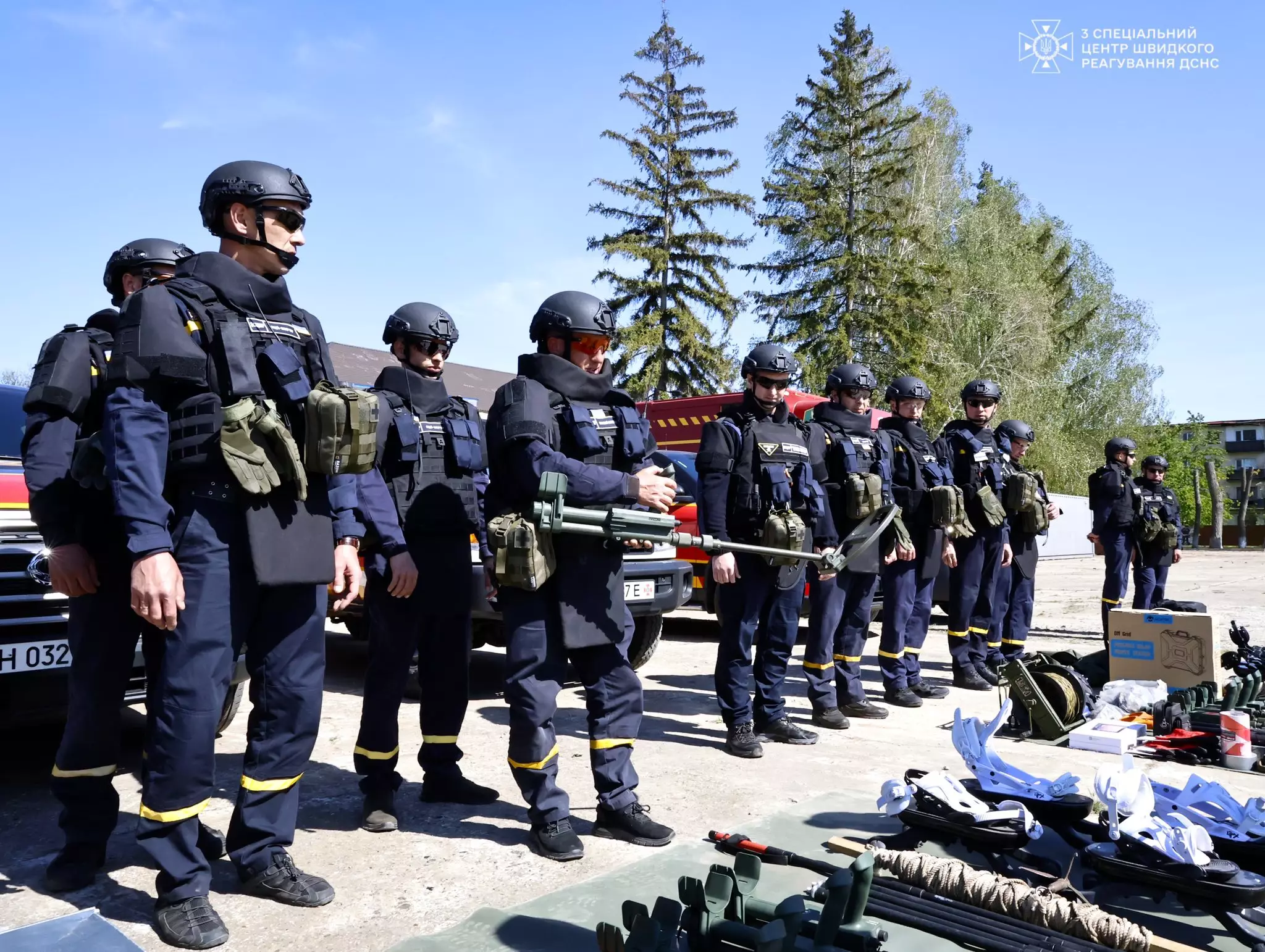 На фото зображені піротехніки у повному екіпіруванні та на фоні автомобілів