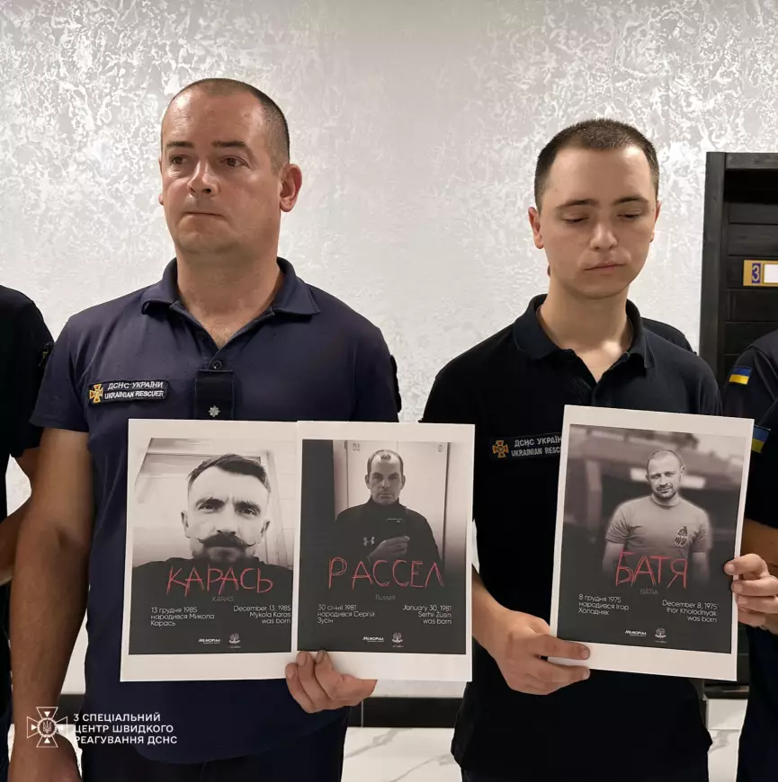 На фото два рятувальники крупним планом, тримають портрети загиблих ГЕРОЇВ