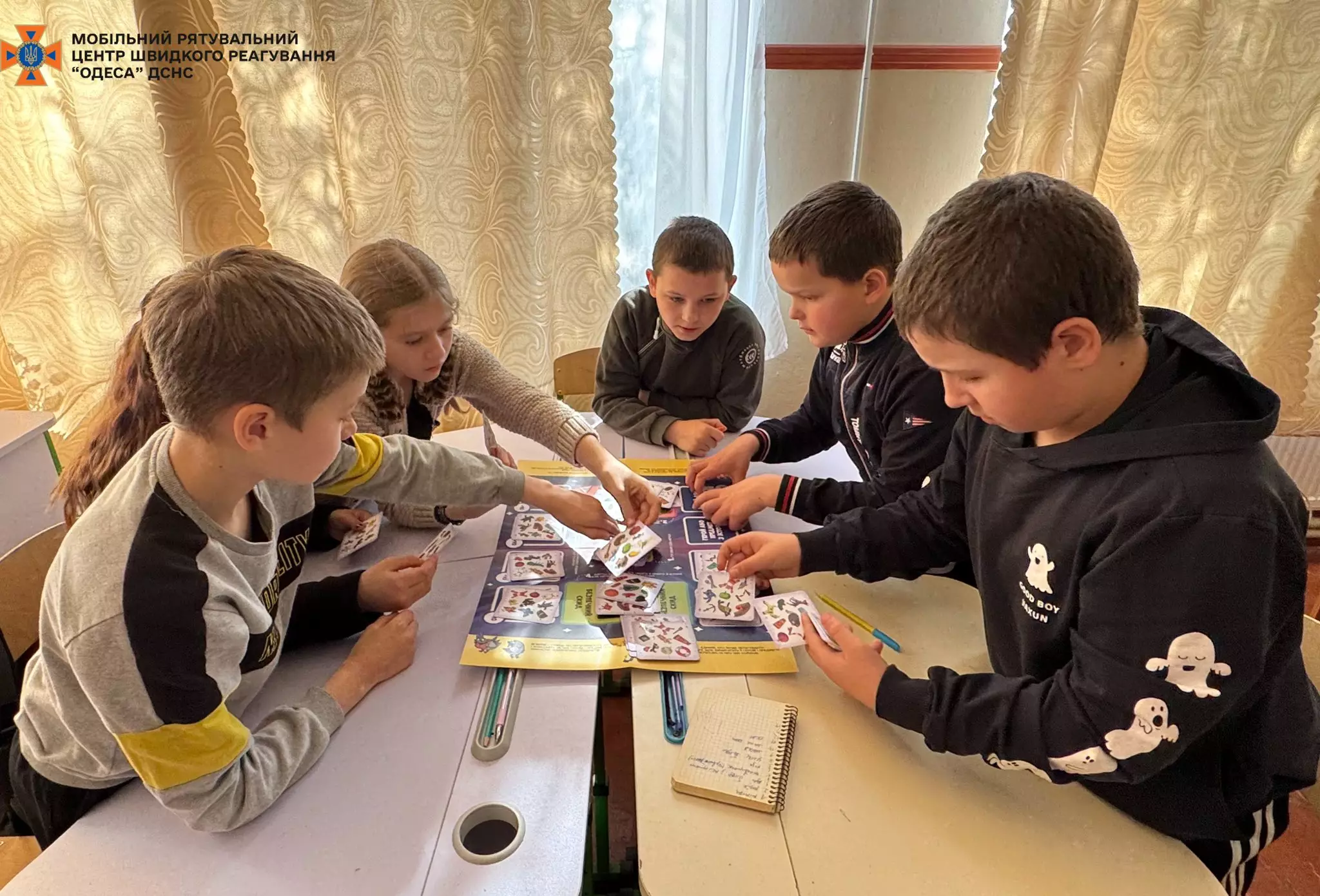 На фото команда з шести учнів викладає картки гри Прогулянка з Патроном