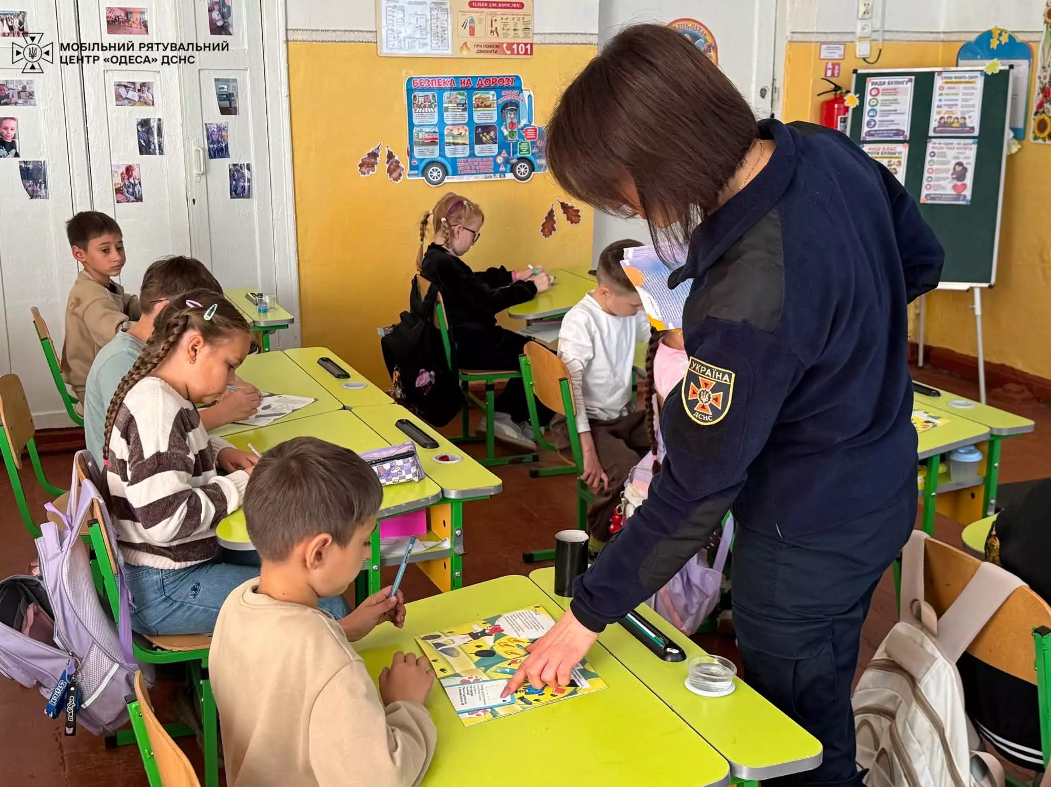 На фото рятувальниця пояснює учневі, як виконати завдання у брошурі - підрахувати кількість вибухонебезпечних предметів