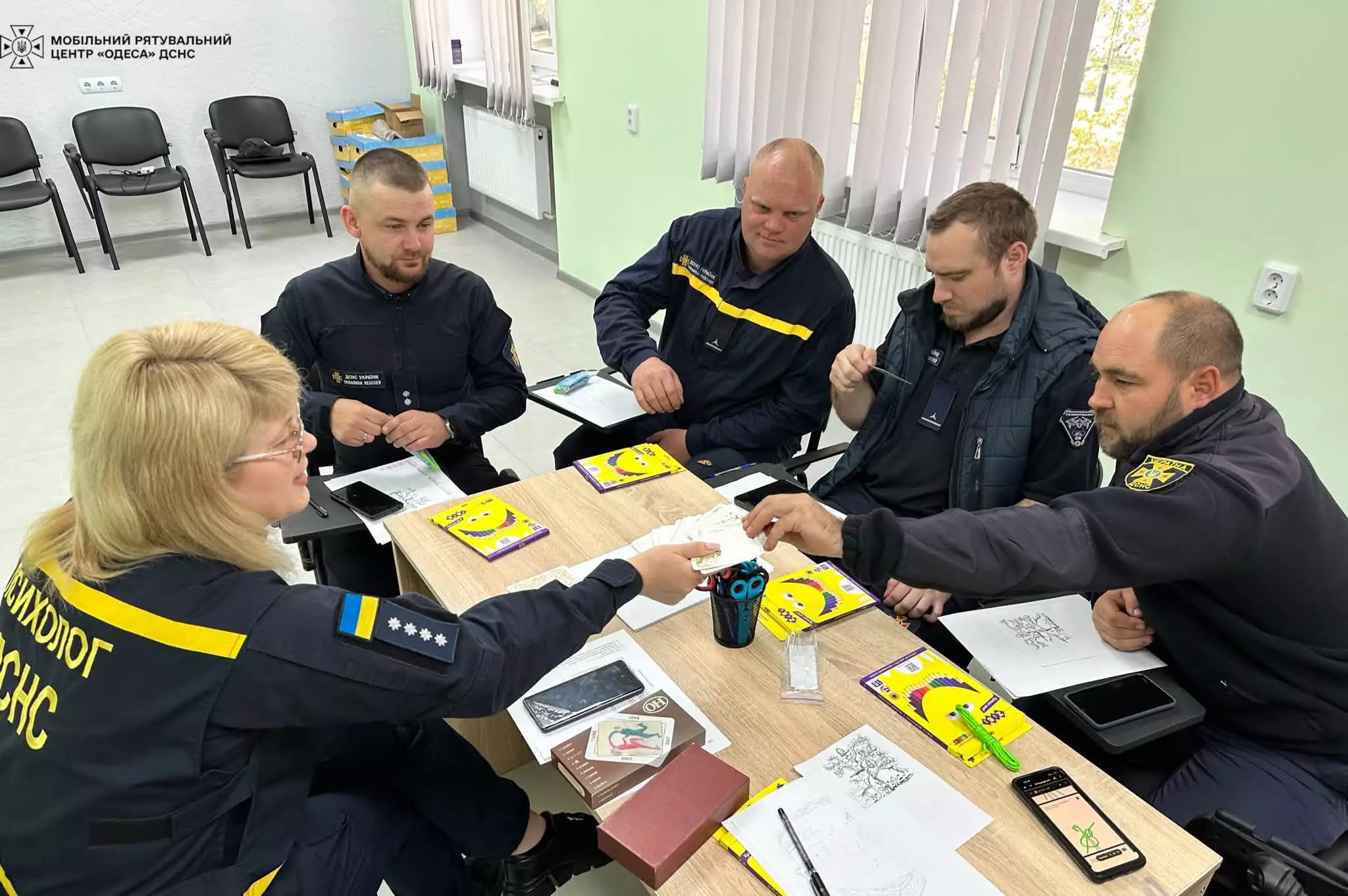 На фото психологиня дає метафоричні карти саеру для вибору однієї