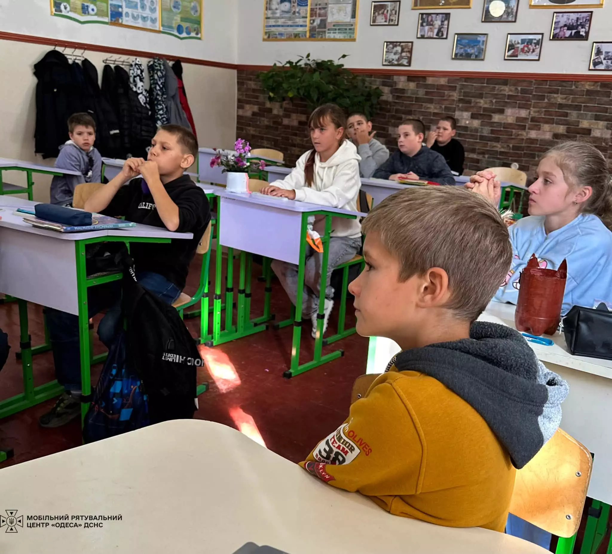 На фото діти за партами, уважно слухають